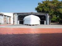 a building has white boats attached to it and brick pavers next to it in front of a blue sky