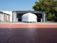 a building has white boats attached to it and brick pavers next to it in front of a blue sky