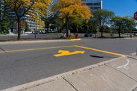 a red stop sign on a curb in front of tall buildings in the city with trees behind it