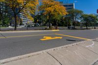 a red stop sign on a curb in front of tall buildings in the city with trees behind it