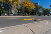 a red stop sign on a curb in front of tall buildings in the city with trees behind it