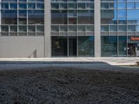 this street is paved and graveled up in front of a building with many windows