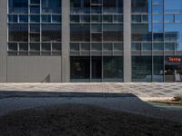 this street is paved and graveled up in front of a building with many windows