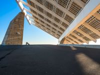 the underside of a roof of a building against a sky background and with sun shining on it