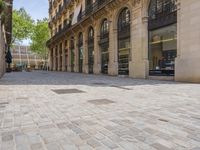 a street with rows of windows and stone pavement in the middle of it with a building near by