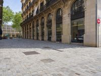 a street with rows of windows and stone pavement in the middle of it with a building near by