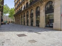 a street with rows of windows and stone pavement in the middle of it with a building near by