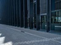 two tall buildings with glass doors at the side of them and a person standing on a sidewalk