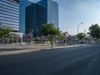 an empty street in front of a building and trees on the other side of the road