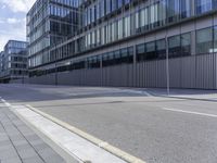 an empty paved street and a building on the other side of the road, which appears to be a square