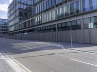 an empty paved street and a building on the other side of the road, which appears to be a square