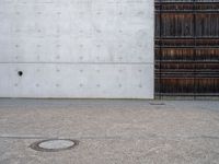 a wooden door and a wall near a brick sidewalk outside of an industrial building with wood panels on the walls