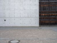 a wooden door and a wall near a brick sidewalk outside of an industrial building with wood panels on the walls