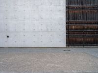 a wooden door and a wall near a brick sidewalk outside of an industrial building with wood panels on the walls