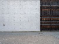 a wooden door and a wall near a brick sidewalk outside of an industrial building with wood panels on the walls