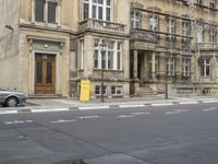 an empty building with signs on the street and people on bikes in traffic passing by