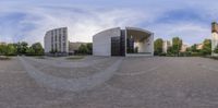 a spherical photo taken in front of some buildings that are connected to one another, with a parking lot below them