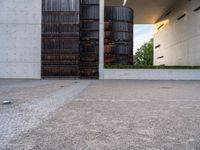 an empty, concrete parking lot under a large structure with tall stacks in the background