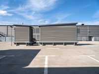 two wooden benches sit side by side in a parking lot outside of a building with stairs and a ramp on each side