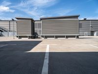 two wooden benches sit side by side in a parking lot outside of a building with stairs and a ramp on each side