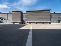 two wooden benches sit side by side in a parking lot outside of a building with stairs and a ramp on each side