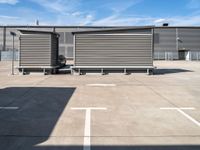 two wooden benches sit side by side in a parking lot outside of a building with stairs and a ramp on each side