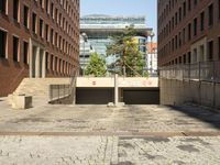 several stone steps lead to an enclosed entrance in a brick courtyard with lots of windows