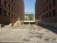 several stone steps lead to an enclosed entrance in a brick courtyard with lots of windows