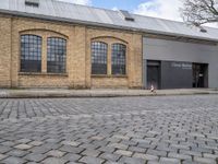 the man is skateboarding on a cobblestone street outside of the warehouse where they have just finished their work