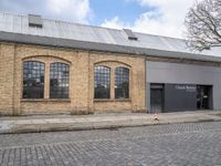 the man is skateboarding on a cobblestone street outside of the warehouse where they have just finished their work