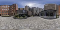 a building is pictured in a 360 - view image with buildings in the background while onlookers are visible