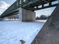 there is a snow covered ground with some stairs in front of it in the background, on which one can be seen a concrete structure and a long bridge