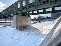 there is a snow covered ground with some stairs in front of it in the background, on which one can be seen a concrete structure and a long bridge