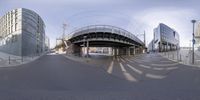 a fish - eye view of buildings and the street under the bridge in front of the camera