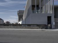 the wall is near an outside building with graffiti on it near a sidewalk next to a fence