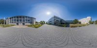 a 360 - view of a building, street and parking lot under the sun in a circular image