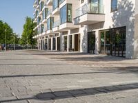 a small child riding a skateboard down a cobblestone sidewalk in front of a tall building