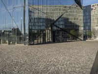 a person is taking their photograph in front of the glass walled building on a bricked street