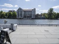 a person is walking on a sidewalk next to a building by the water at a dock