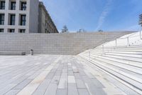 stone stairs, flanked by white wall with buildings in the background, with concrete steps leading up to it and a sign that reads u s i don't s