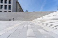 stone stairs, flanked by white wall with buildings in the background, with concrete steps leading up to it and a sign that reads u s i don't s