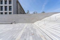 stone stairs, flanked by white wall with buildings in the background, with concrete steps leading up to it and a sign that reads u s i don't s