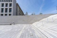 stone stairs, flanked by white wall with buildings in the background, with concrete steps leading up to it and a sign that reads u s i don't s