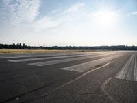 an empty runway that has no cars on it and clouds in the background with trees