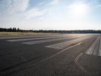 an empty runway that has no cars on it and clouds in the background with trees