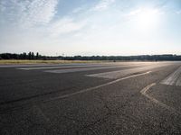 an empty runway that has no cars on it and clouds in the background with trees