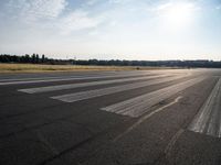 an empty runway that has no cars on it and clouds in the background with trees