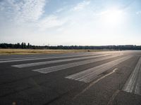 an empty runway that has no cars on it and clouds in the background with trees