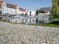 a fire hydrant is shown near a body of water in a city square with boats on the water