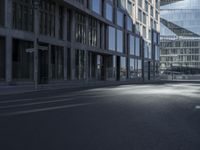 the empty road is lined with tall buildings near some glass doors by the window sills